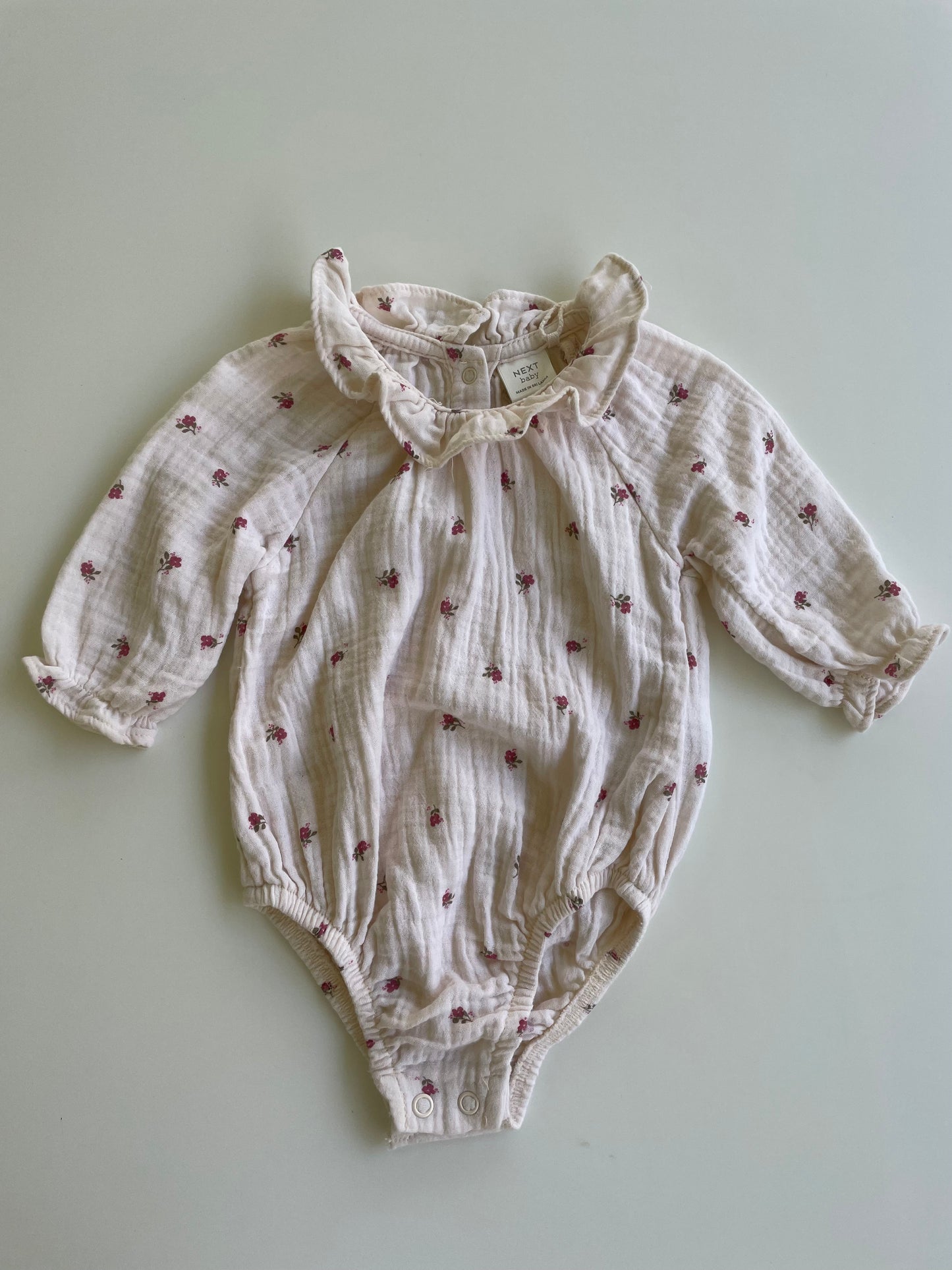 Baby romper with floral pattern on a light gray background