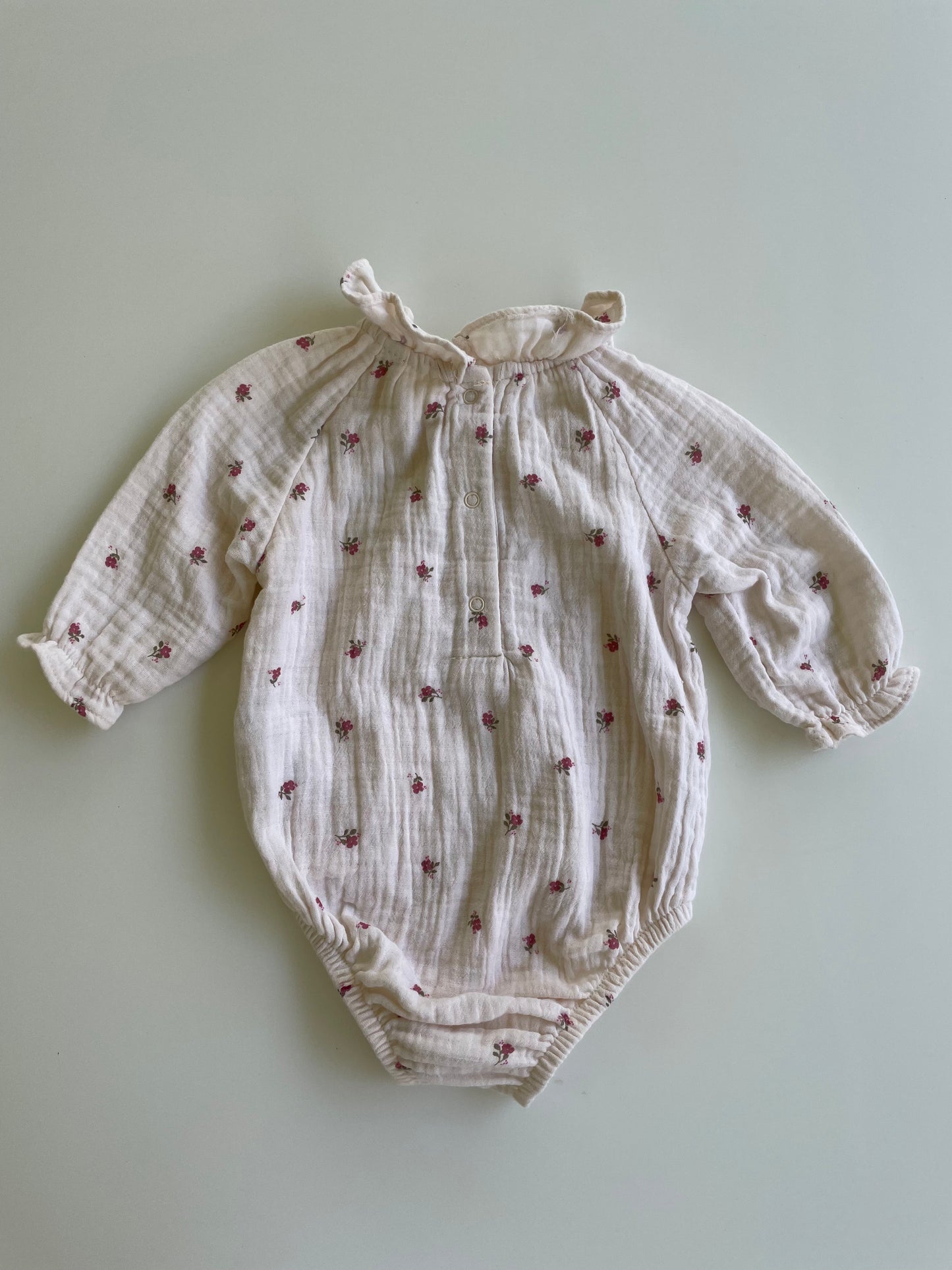 Baby romper with floral pattern on a light green background